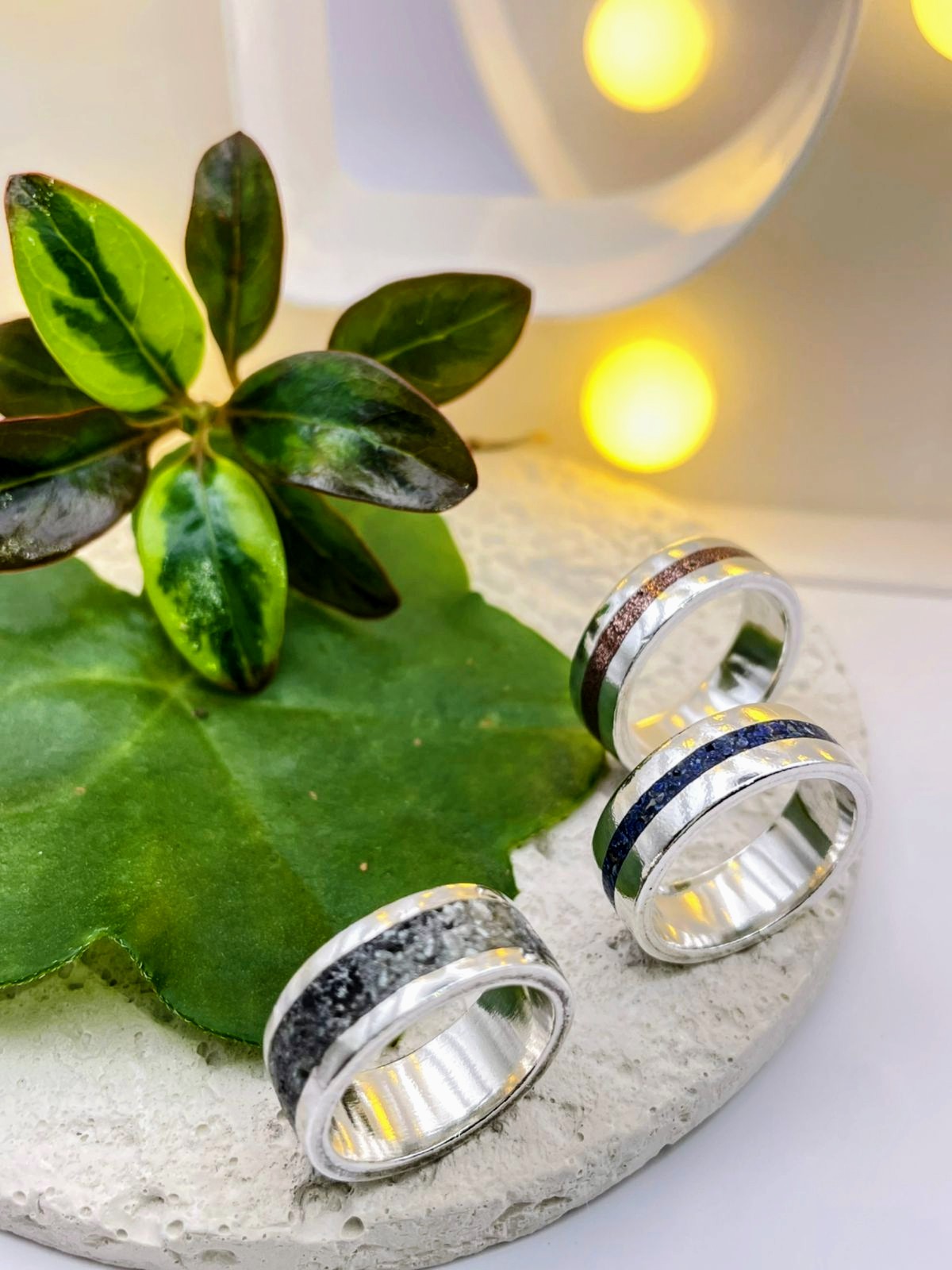 Dos anillos de plata terminados sobre una hoja verde, con luces doradas de fondo
